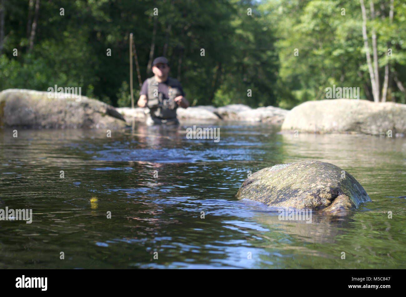 Fly fishermen in a French trout river. Fly fishing scene focused on fly fishing lure. Stock Photo