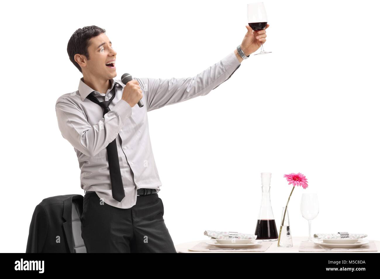 Drunk man holding a glass of wine and singing on a microphone isolated on white background Stock Photo