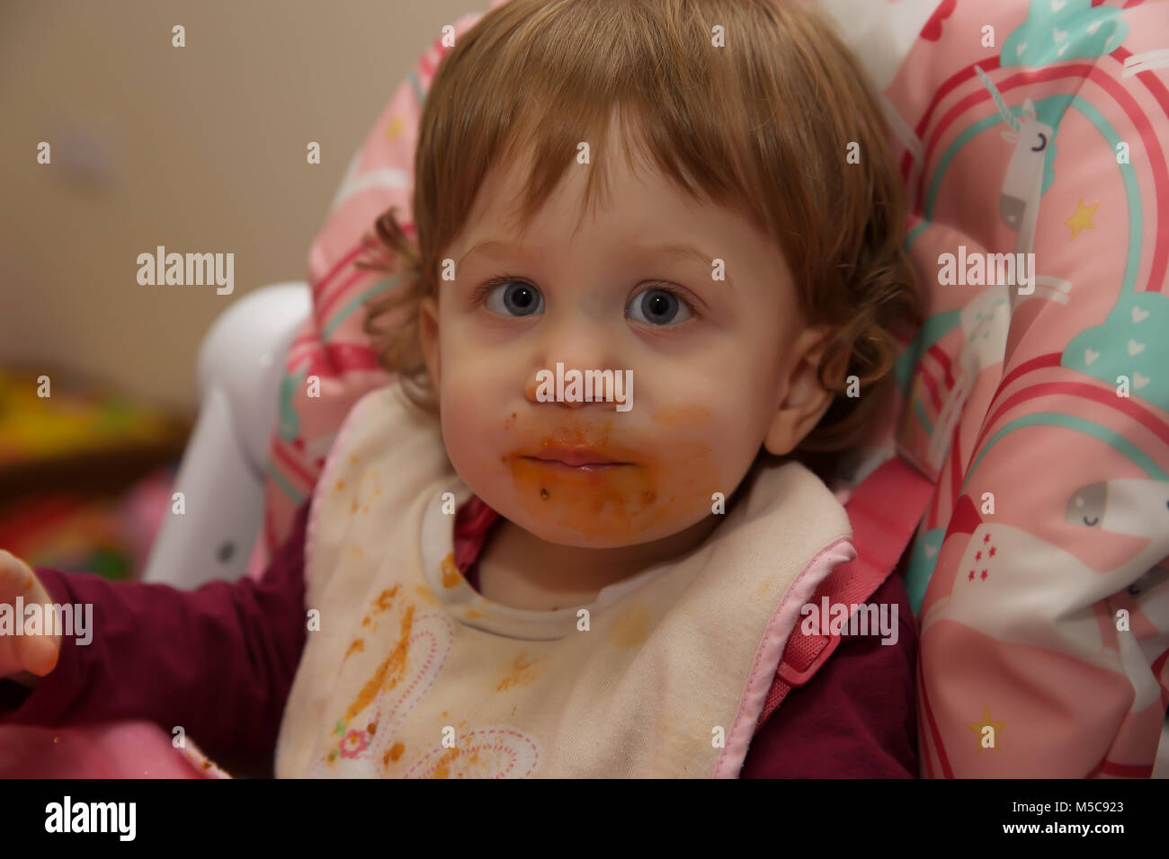 A female toddler with a messy face after eating Spaghetti Bolognaise