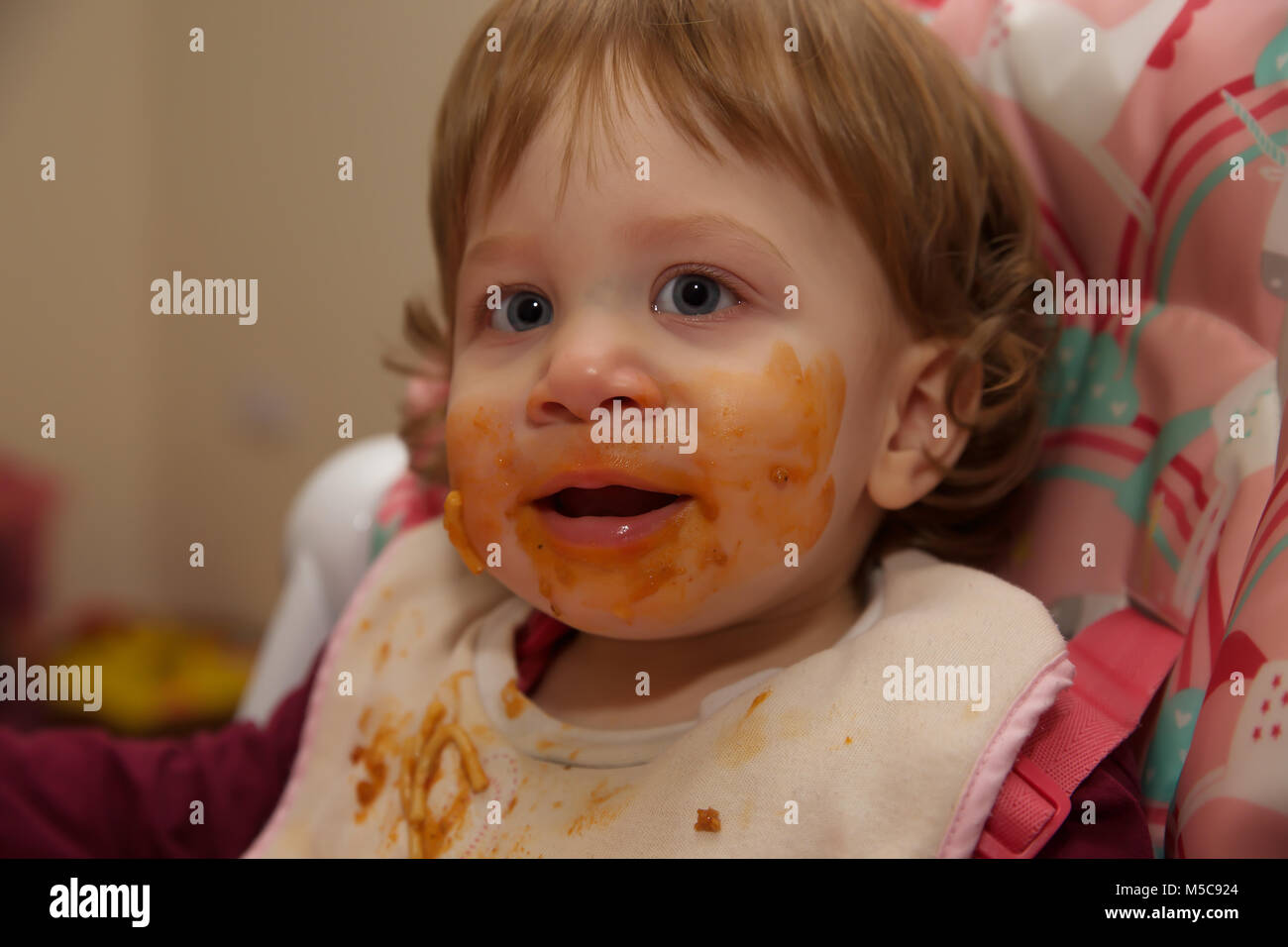 A female toddler with a messy face after eating Spaghetti Bolognaise