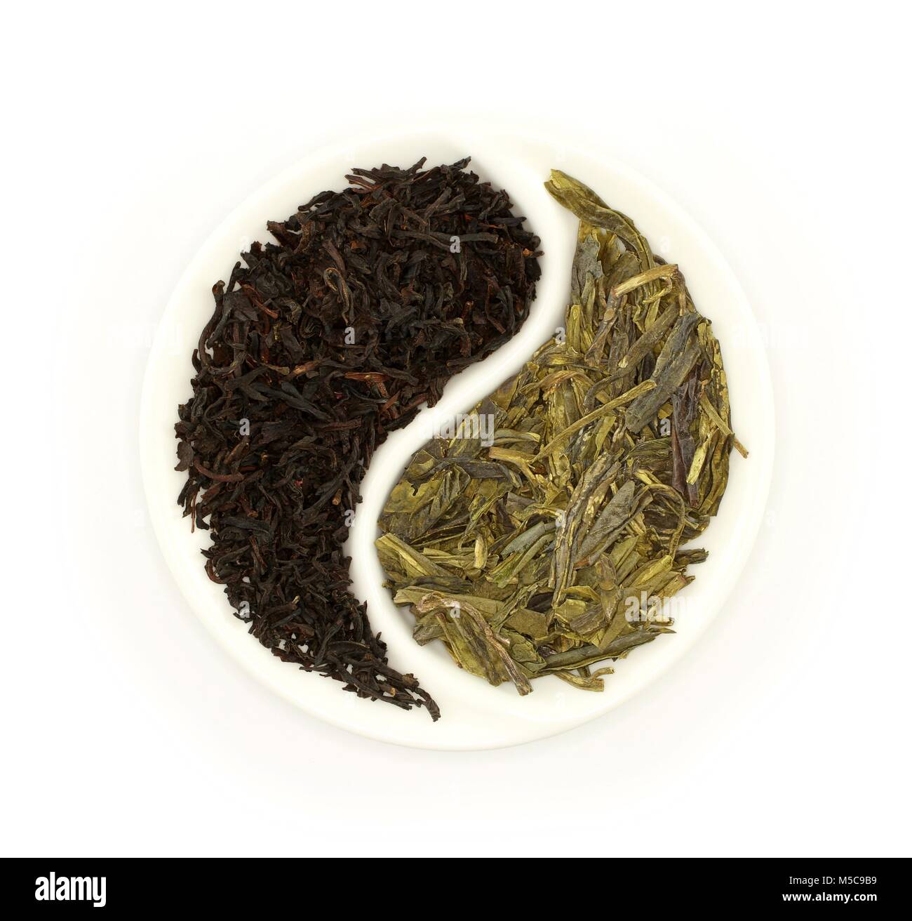 Green tea and black tea in round Yin and Yang white saucer on white