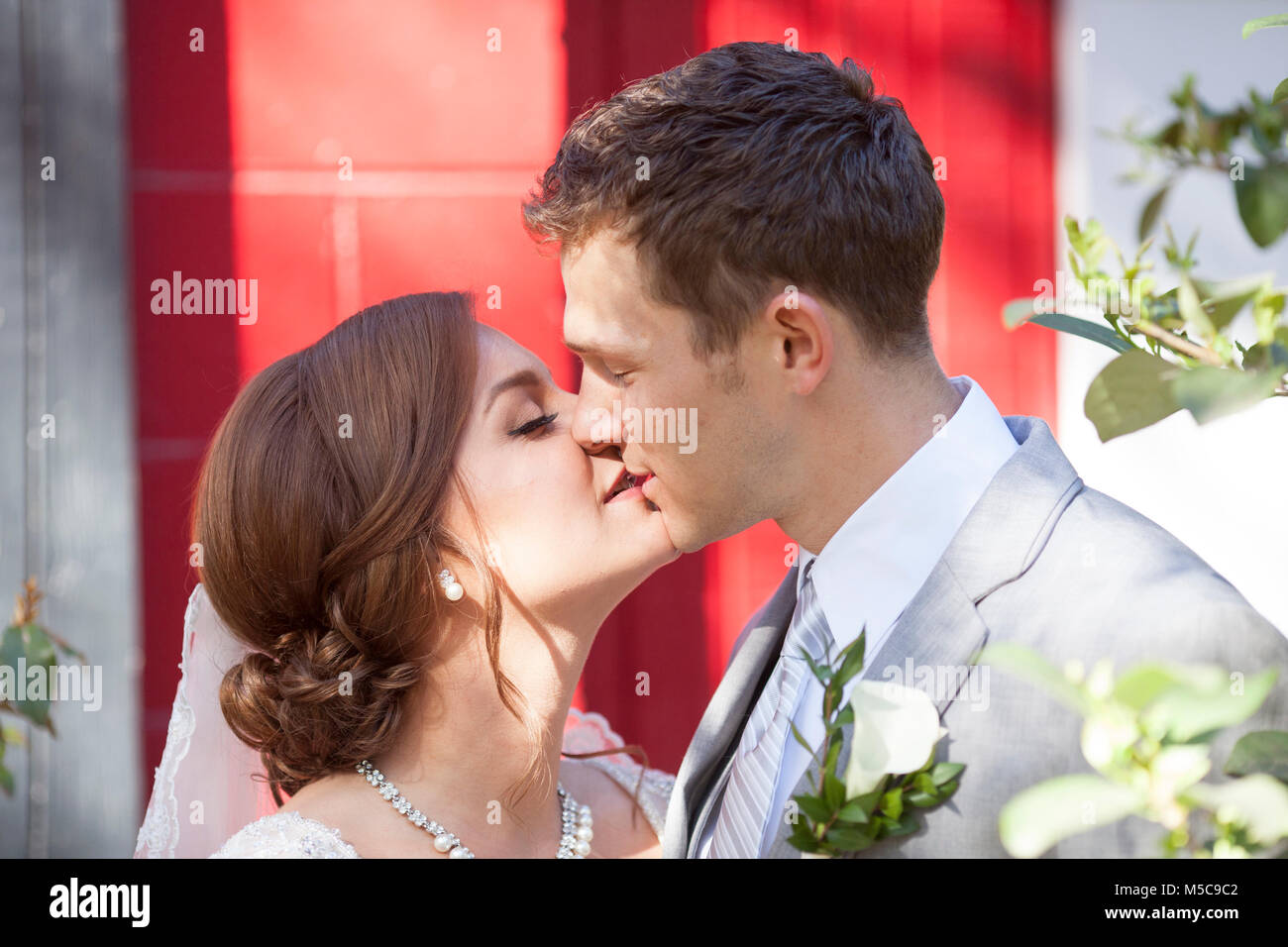 Bride and groom kissing in garden Stock Photo - Alamy