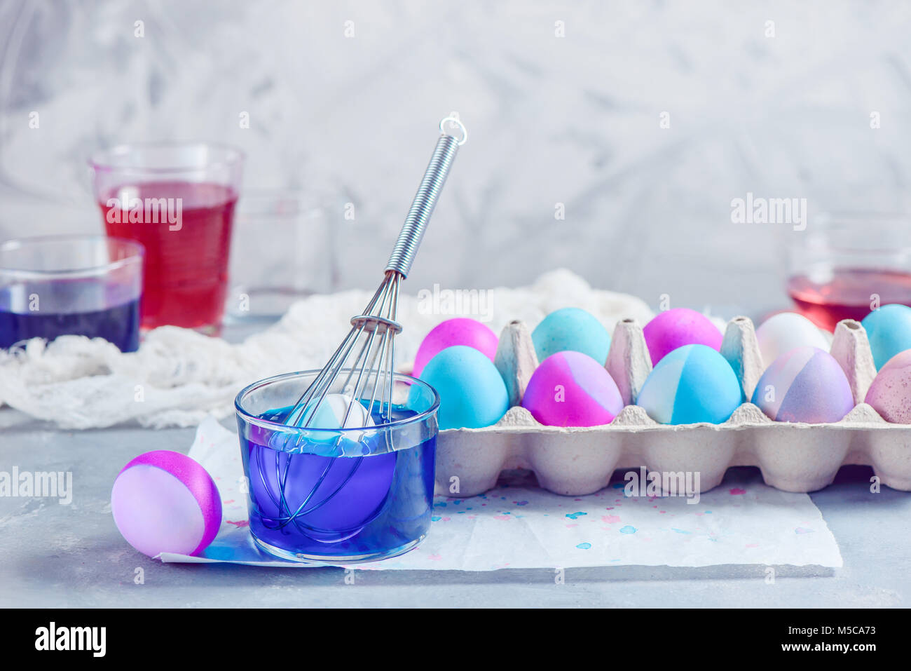 Painting Easter eggs with a whisk. Minimalist holiday decorating. Easy Easter lifehack with copy space. Stock Photo