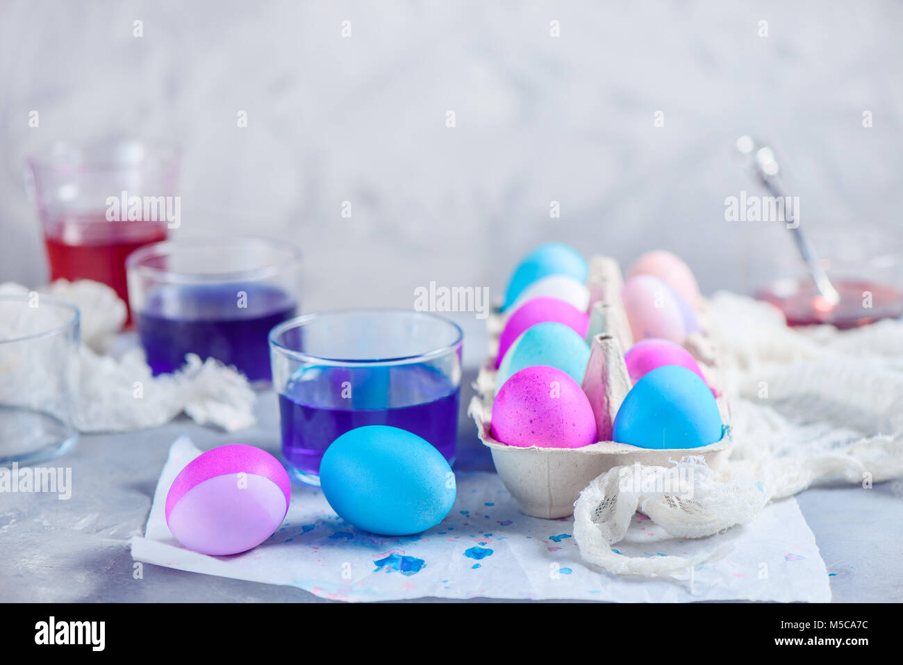Happy Easter background with copy space. Easter eggs in a paper carton. Modern high key holiday scene with shades of blue and purple. Stock Photo