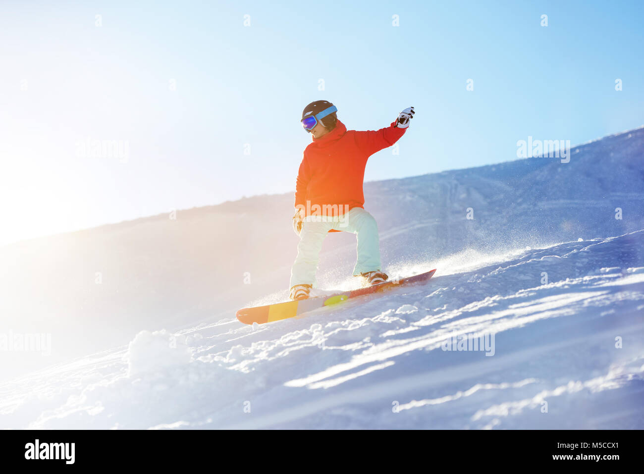 Lady snowboarder at ski slope in sun light Stock Photo