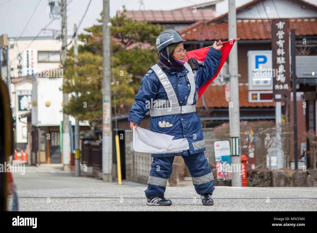 A Japanese road worker directing traffic in the middle of Takayama.Takayama is a city in Japan's mountainous Gifu Prefecture Stock Photo