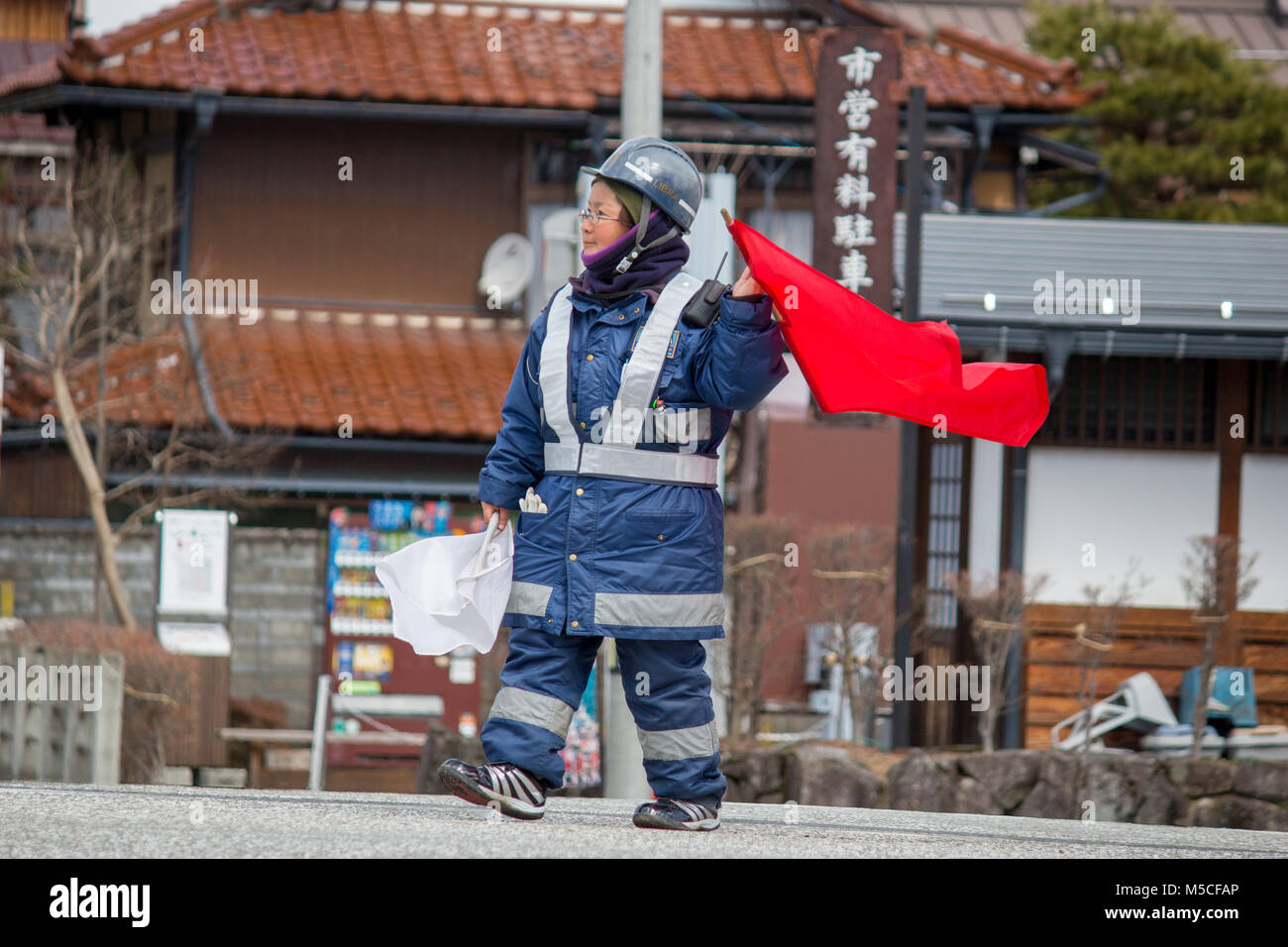 A Japanese road worker directing traffic in the middle of Takayama.Takayama is a city in Japan's mountainous Gifu Prefecture Stock Photo