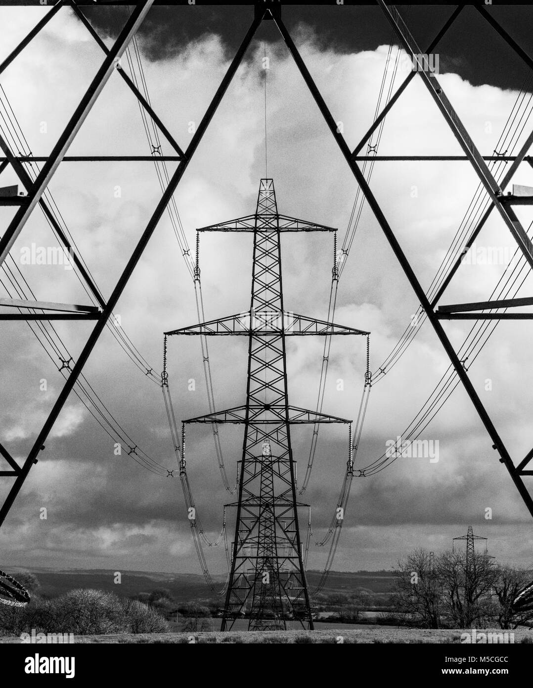Electricity pylons crossing the countryside in Carmarthenshire, west Wales. UK. (High contrast B/W applied in post) Stock Photo