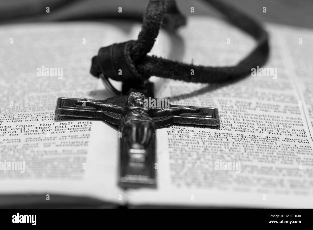 Crucifix necklace on a bible page with wood background in black and white Stock Photo
