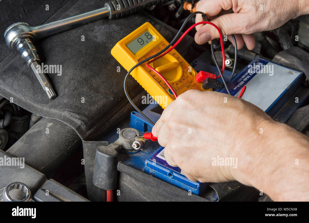 Measuring voltage on car battery. Change weak battery Stock Photo Alamy