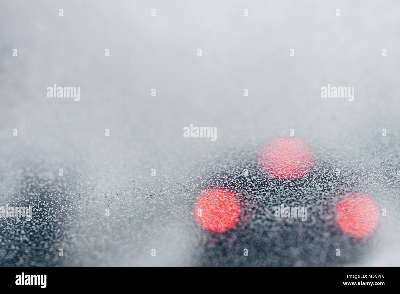 Closeup frosty car windshield. Blurred background. Red car brake