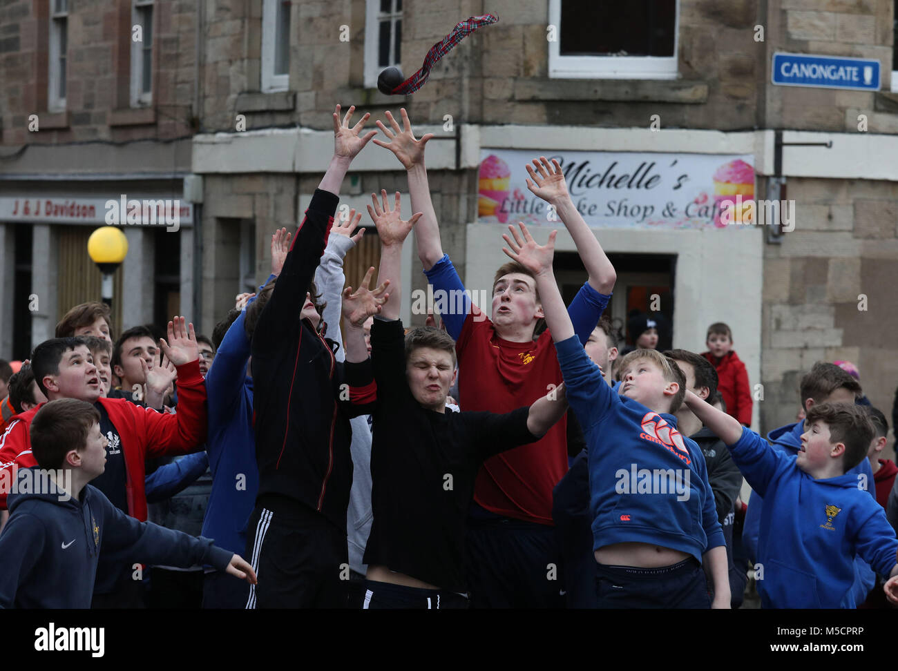 Boys tussle for the leather ball during the annual 'Fastern Eve Handba' event on Jedburgh's High Street in the Scottish Borders. The annual event, which started in the 1700's, involves two teams, the Uppies (residents from the higher part of Jedburgh) and the Doonies (residents from the lower part of Jedburgh) getting the ball to either the top or bottom of the town. The ball, which is made of leather, stuffed with straw and decorated with ribbons is thrown into the crowd to begin the game. Photo credit should read: Andrew Milligan/PA Wire. Stock Photo