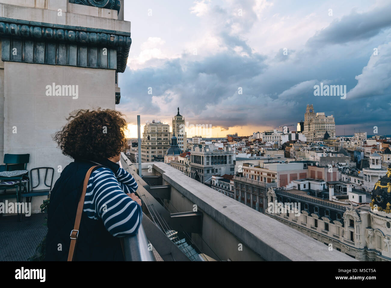 Madrid, Spain - November 3, 2017:  Woman looking at skyline at rooftop on Circulo de Bellas Artes of Madrid at sunset. Stock Photo
