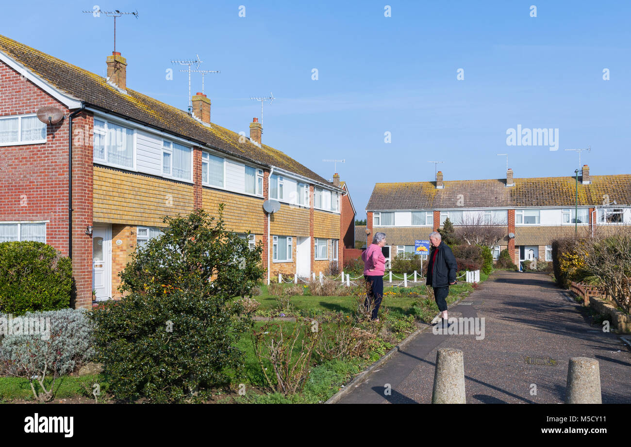 Pair of neighbours standing outside talking, in a close in England, UK. Neighbors chatting. Stock Photo