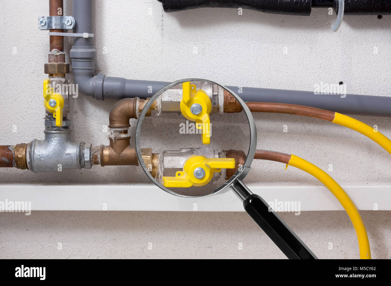 Copper and plastic pipes and yellow valves in a boiler room under the