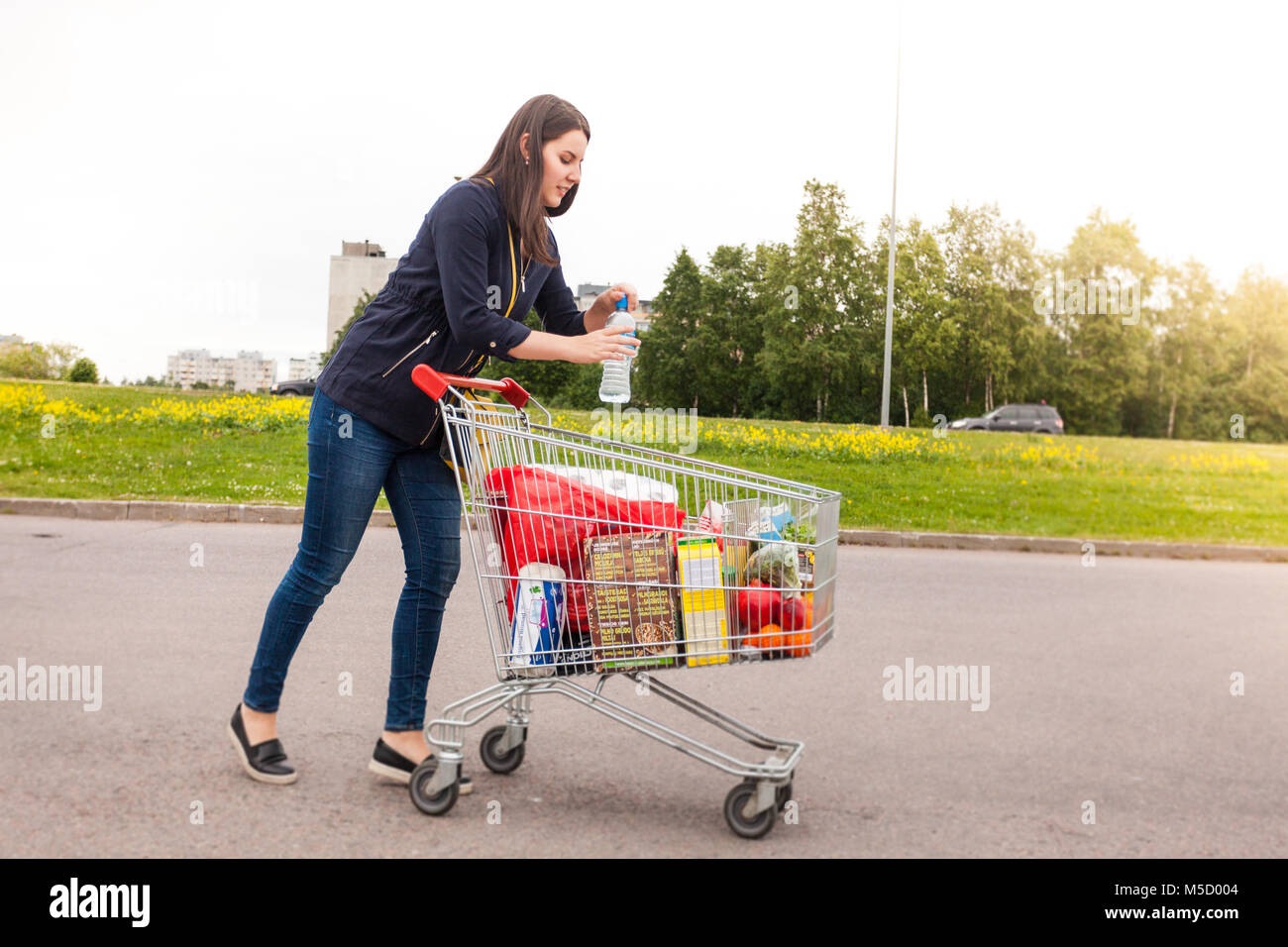Happy pretty girl takes a water from shopping cart Stock Photo