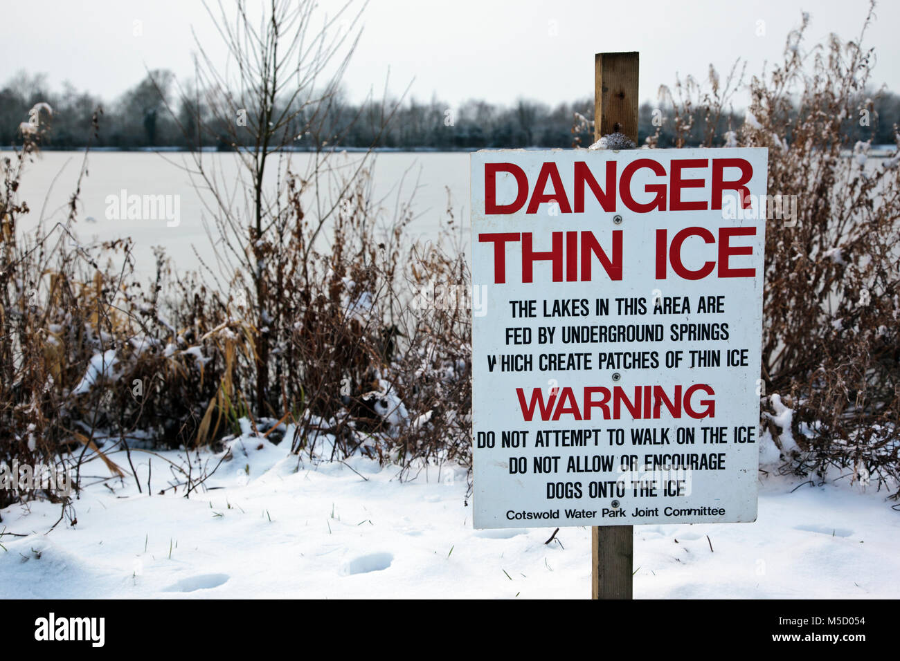 Danger Thin Ice warning sign next to a frozen lake at Neighbridge Country Park near Somerford Keynes in the Costwold Water Park Stock Photo
