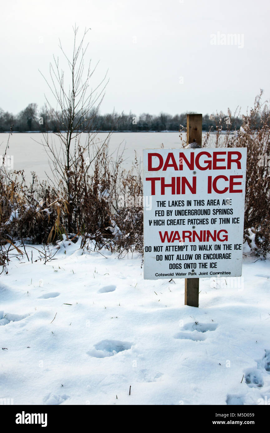 Danger Thin Ice warning sign next to a frozen lake at Neighbridge Country Park near Somerford Keynes in the Costwold Water Park Stock Photo
