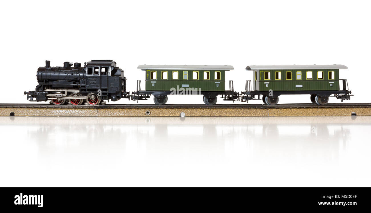 Vintage model electric train formed by a steam locomotive and two passenger cars on the rails Stock Photo