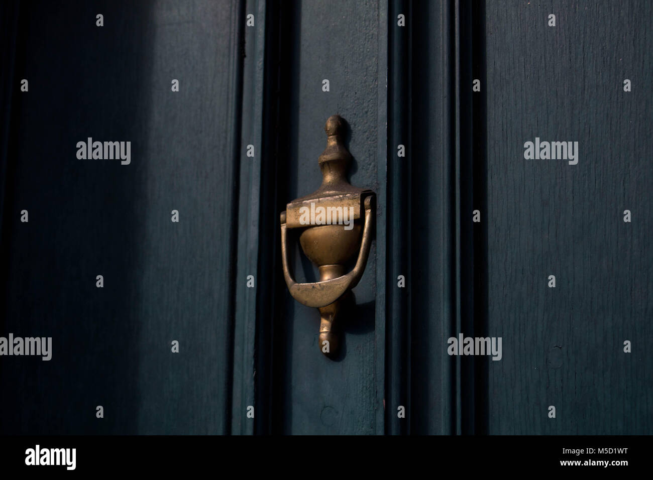 Traditional brass door knocker on a dark blue toned door, close up in