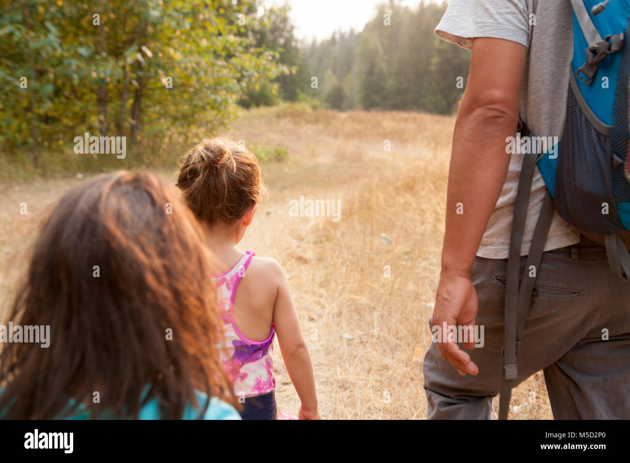 Father and daughters hiking on sunny path Stock Photo
