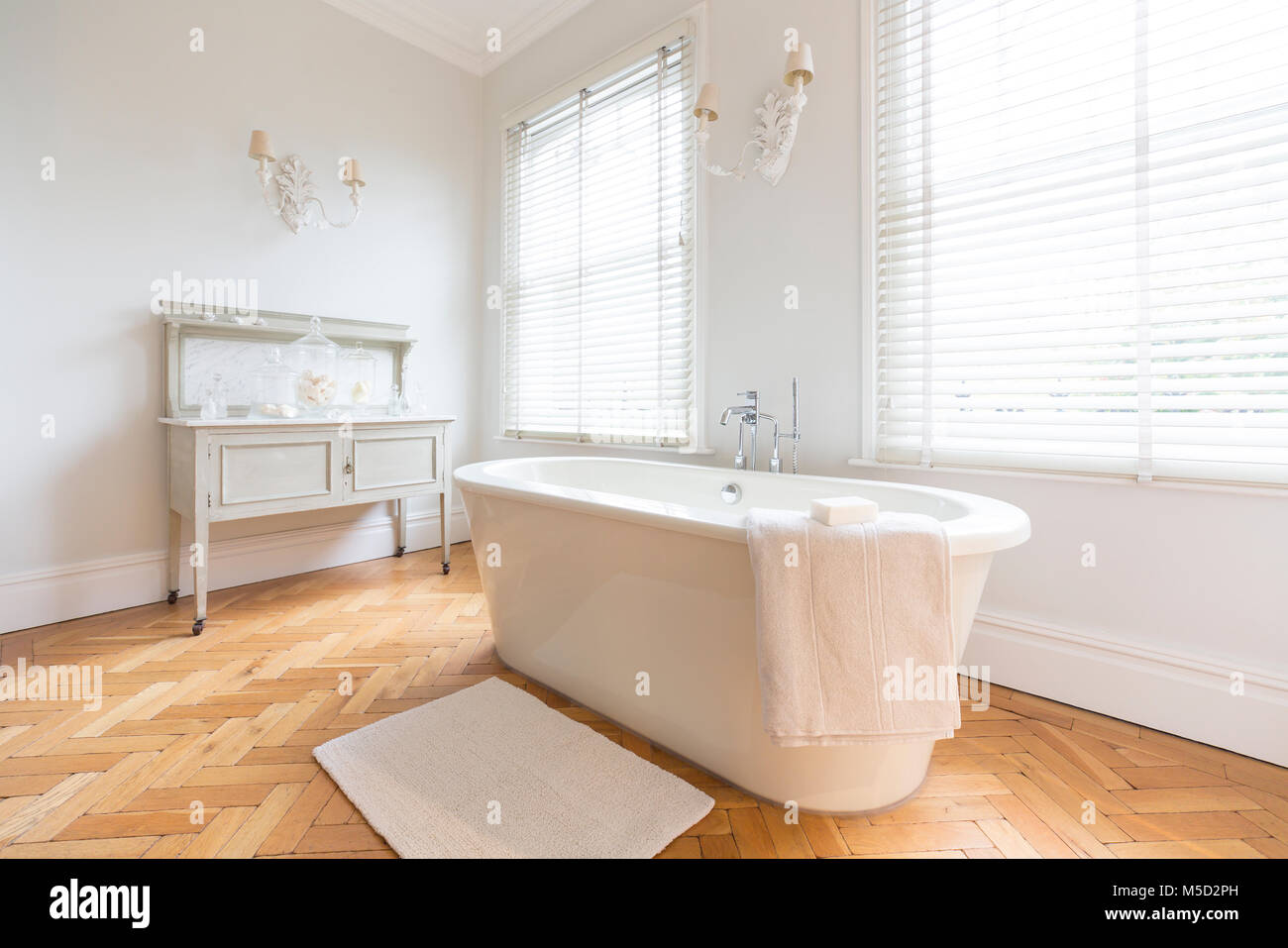 White, luxury home showcase interior bathroom with soaking tub and parquet hardwood floor Stock Photo