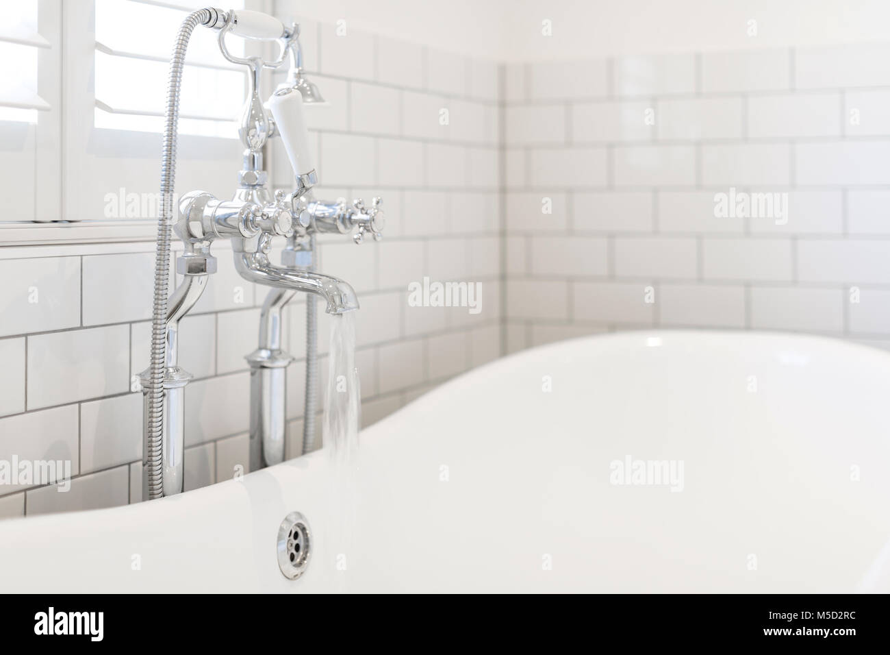 Water running from bathroom faucet into white soaking tub Stock Photo