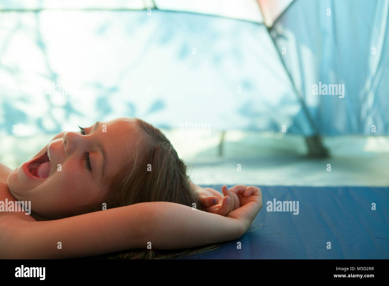 Tired girl yawning, resting inside tent Stock Photo