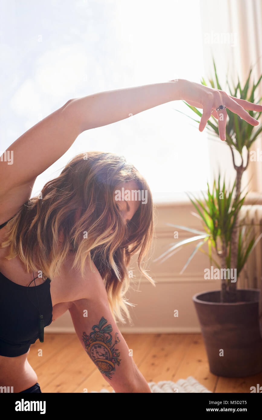 Woman with tattoo practicing yoga side body stretch Stock Photo
