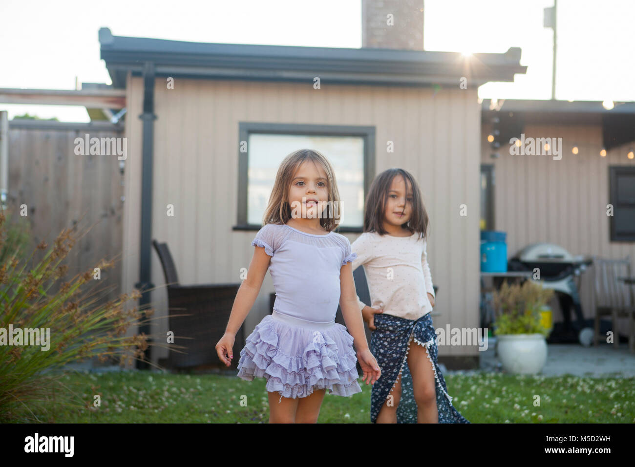 Portrait girl sisters in skirts in yard Stock Photo