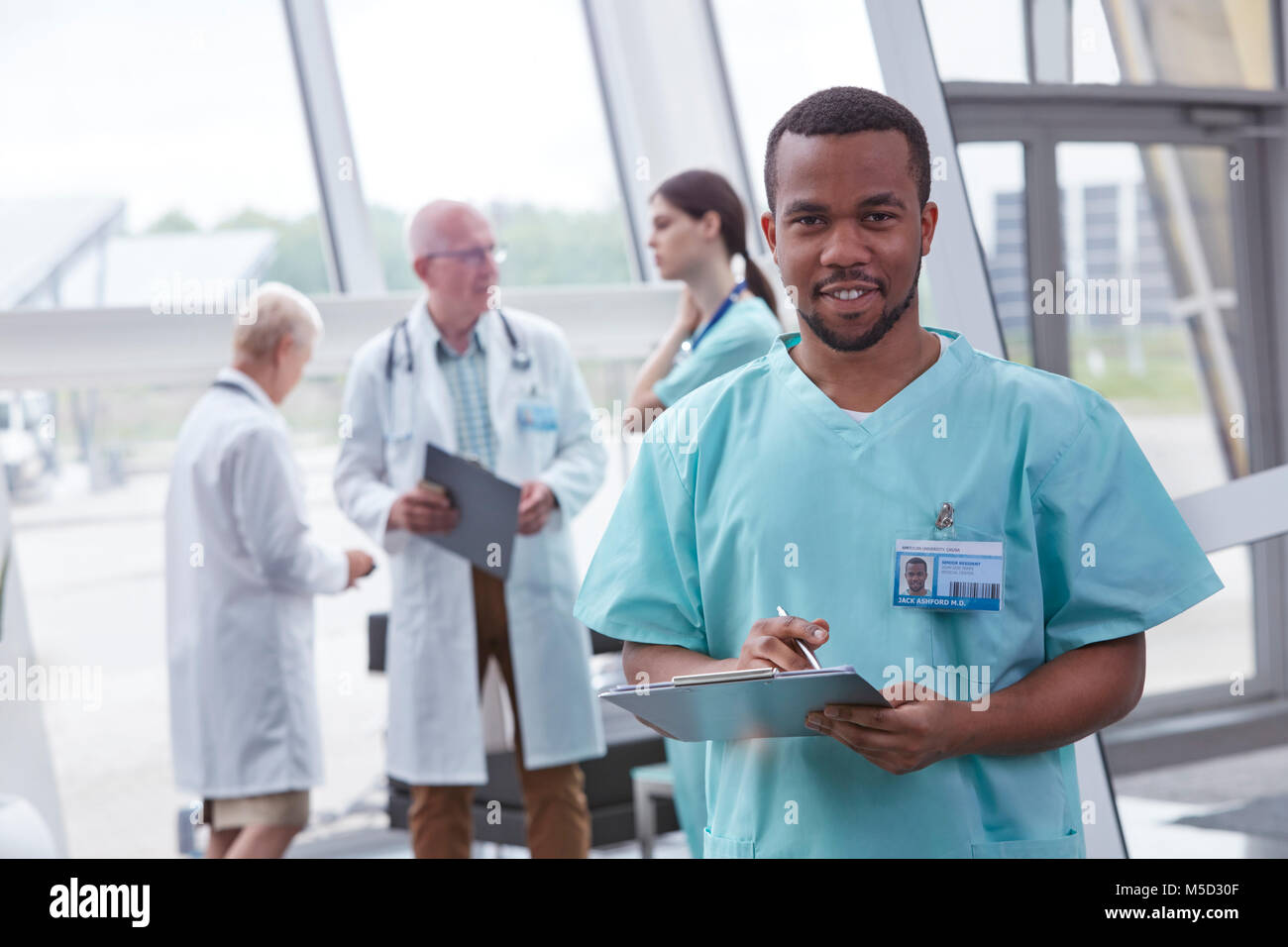 Portrait confident male nurse with clipboard in hospital lobby Stock Photo