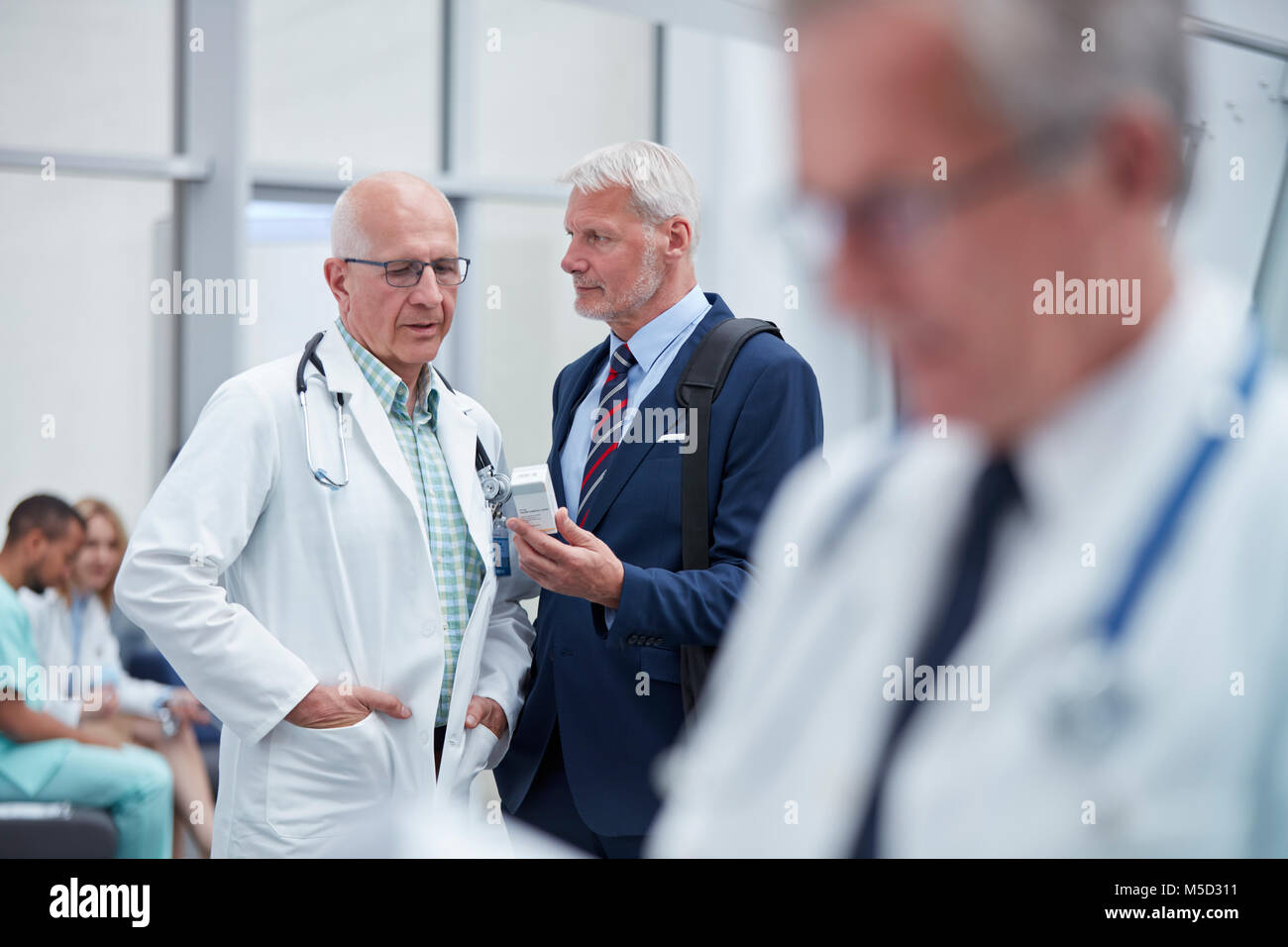 Male pharmaceutical representative showing prescription medication to doctor in hospital Stock Photo