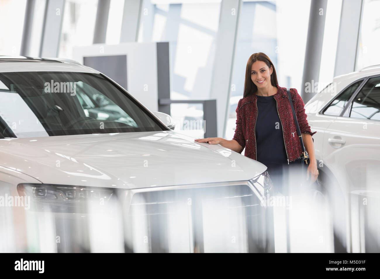 Portrait smiling female customer browsing new cars in car dealership showroom Stock Photo