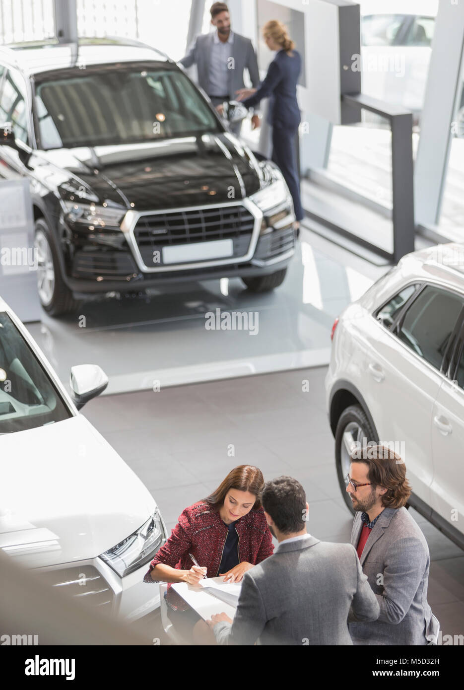 Car sales people and customers in car dealership showroom Stock Photo