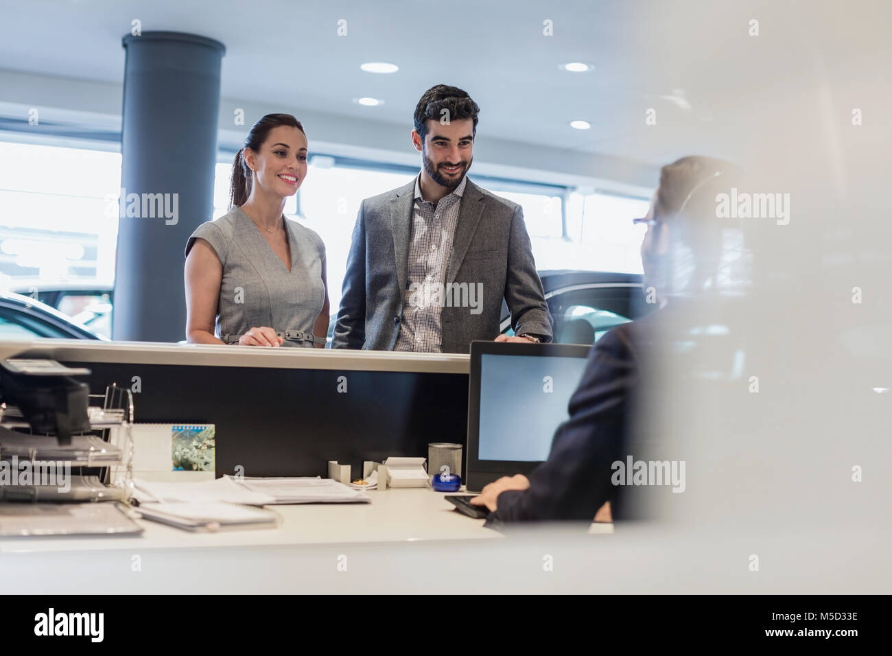 Couple at reception desk in car dealership showroom Stock Photo