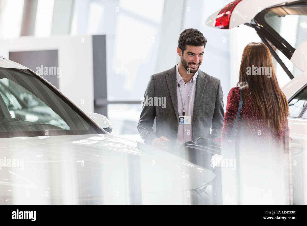 Car salesman helping female customer in car dealership showroom Stock Photo