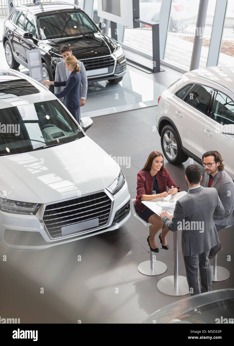 Car sales people meeting at table in car dealership showroom Stock Photo