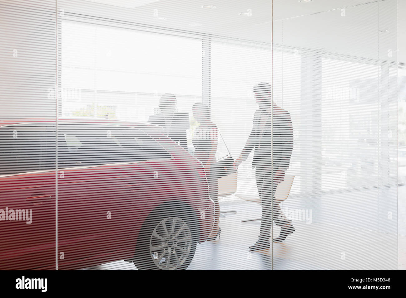 Car salesman showing new car to customers in car dealership showroom Stock Photo