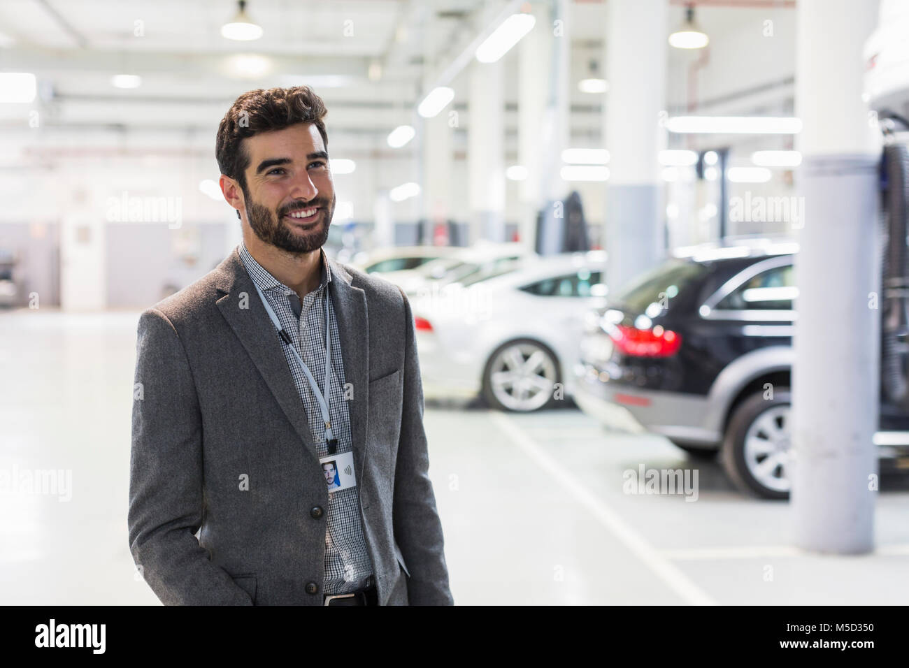 Portrait smiling car salesman looking away in car dealership auto repair shop Stock Photo