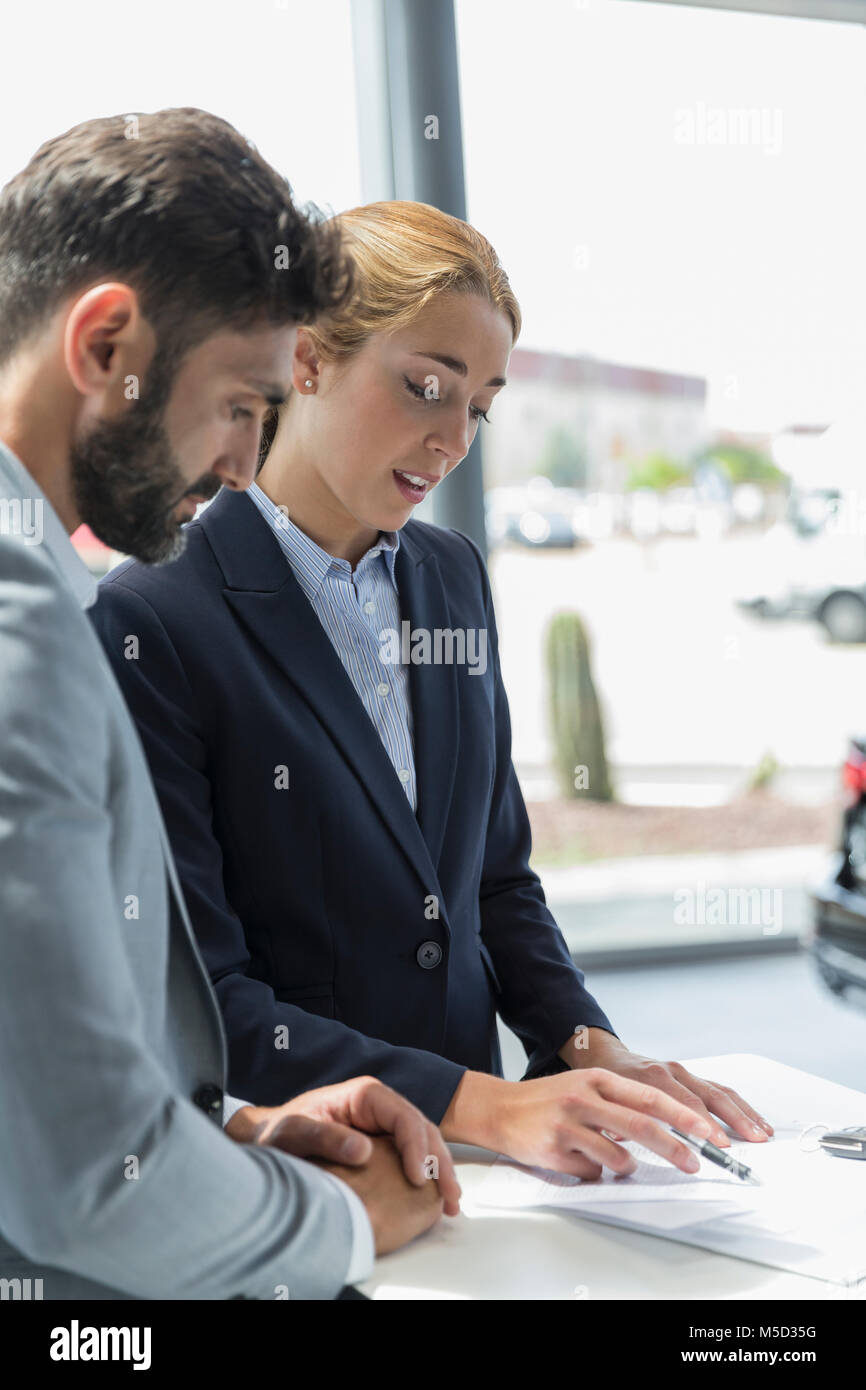 Car saleswoman explaining financial contract paperwork in car dealership Stock Photo