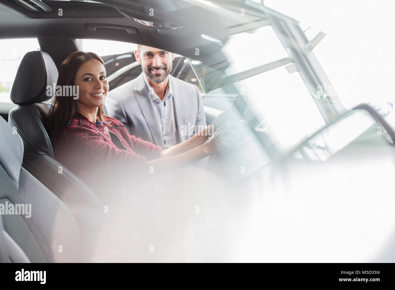 Portrait smiling car salesman and female customer in driver’s seat of new car in car dealership Stock Photo