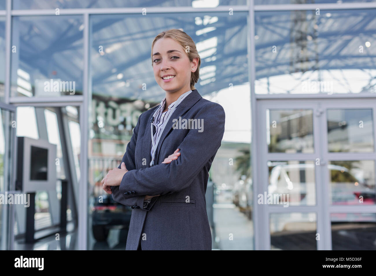 Portrait confident, smiling car saleswoman standing outside of car dealership showroom Stock Photo