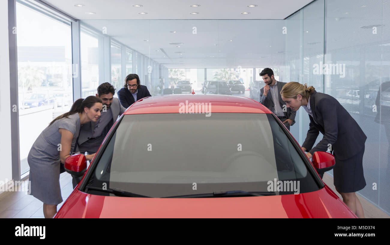 Customers looking at new car in car dealership showroom Stock Photo