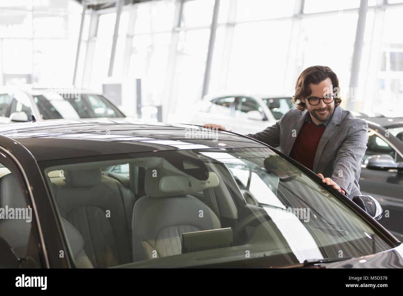 Male customer eyeing new car in car dealership showroom Stock Photo