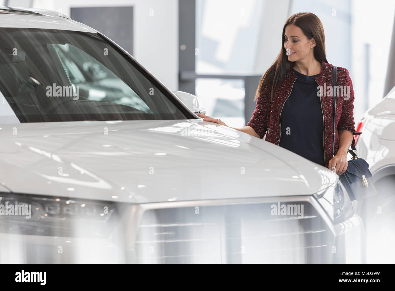 Female customer shopping for new car in car dealership showroom Stock Photo