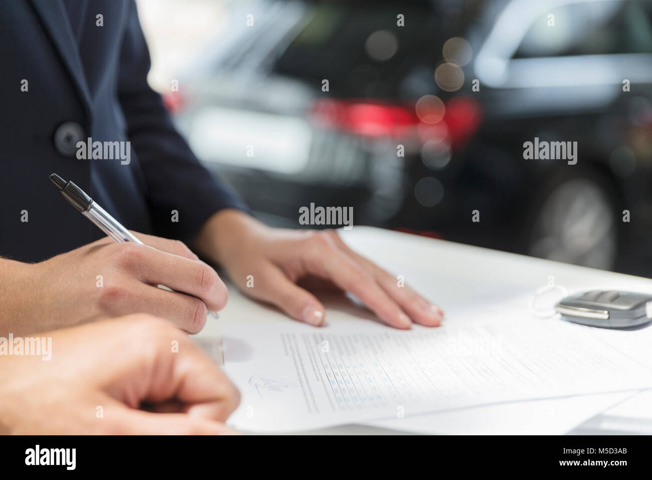 Close up customer signing financial contract paperwork in car dealership Stock Photo