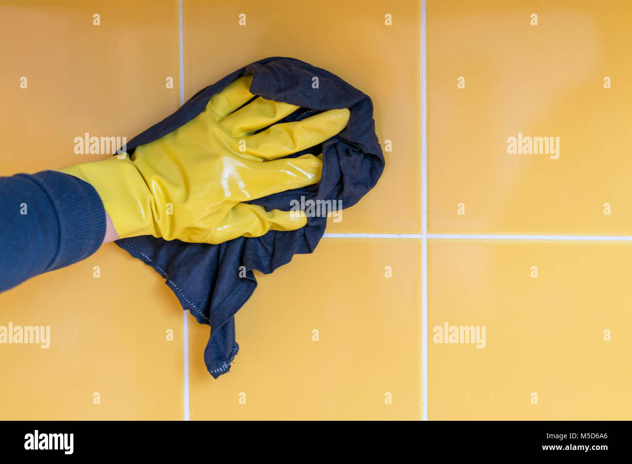 hand in a yellow rubber glove washes a yellow wall with a rag Stock ...