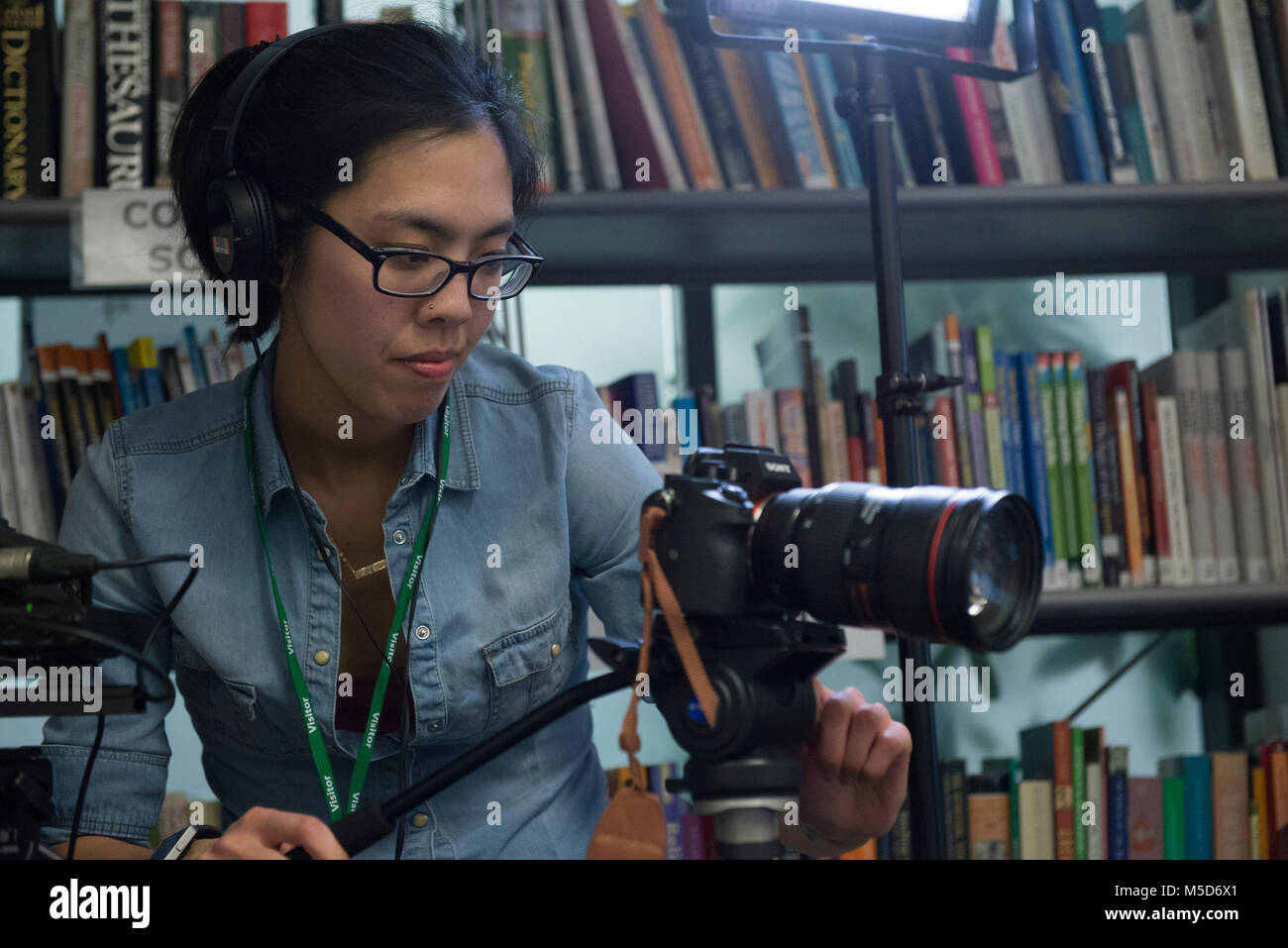 students on college campus take part in an organised social event in the library and are filmed for an online video while being interviewed Stock Photo
