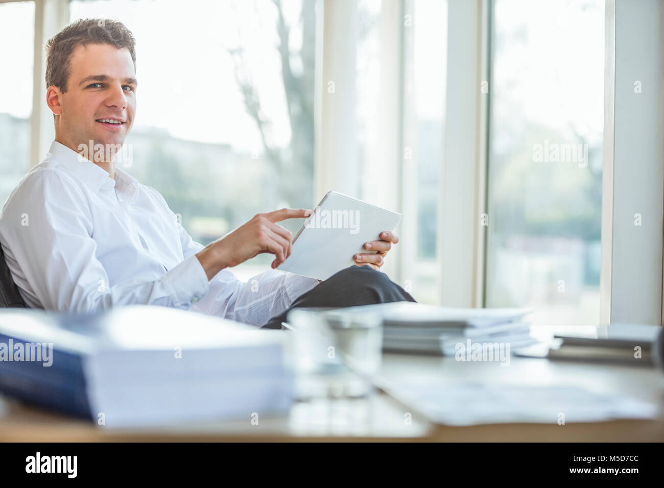 Portrait of handsome young businessman using digital tablet in office ...