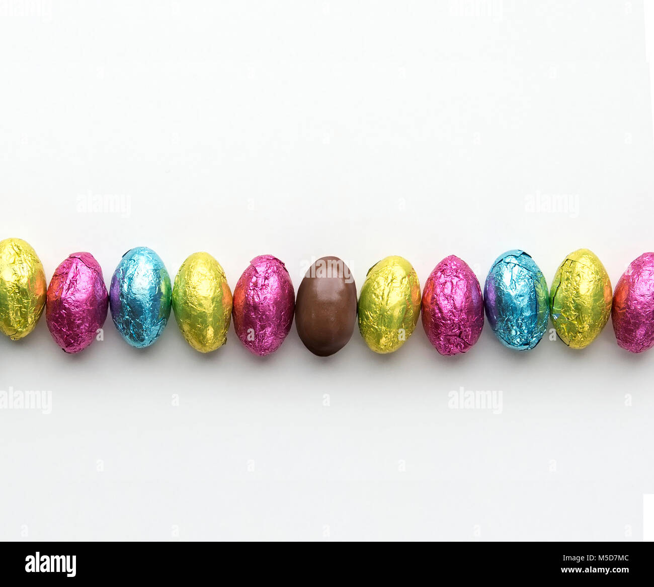 Foil wrapped easter candy in a row one candy unwrapped Stock Photo